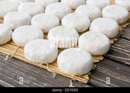 Set of small heads of young goat cheese crottin  lying on wooden boards Stock Photo