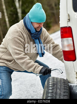 Mid adult man exchanging tire on the road Stock Photo