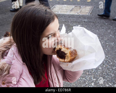 A young girl eats a huge chocolate doughnut Stock Photo