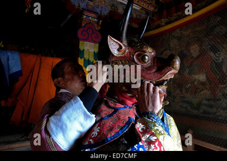 Young man wearing a wooden mask during preparation for the rare and old sacred dance called Zhey not performed elsewhere in Bhutan during the annual religious Bhutanese Tshechu festival in Ngang Lhakhang a Buddhist monastery also known as the 'Swan temple' built in the 16th century by a Tibetan lama named Namkha Samdrip in the Choekhor Valley of Bumthang District central Bhutan Stock Photo