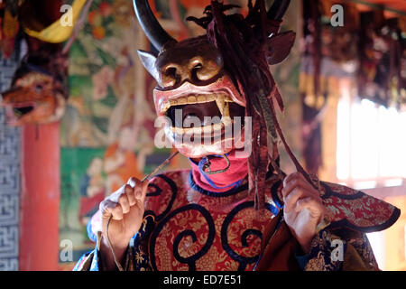 Young man wearing a wooden mask during preparation for the rare and old sacred dance called Zhey not performed elsewhere in Bhutan during the annual religious Bhutanese Tshechu festival in Ngang Lhakhang a Buddhist monastery also known as the 'Swan temple' built in the 16th century by a Tibetan lama named Namkha Samdrip in the Choekhor Valley of Bumthang District central Bhutan Stock Photo