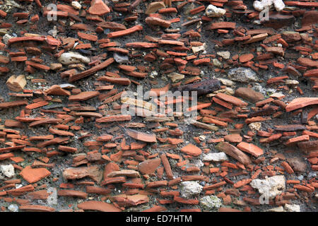 Many layers of different ancient broken clay pieces are trapped in soil, in layers one above the other. Stock Photo