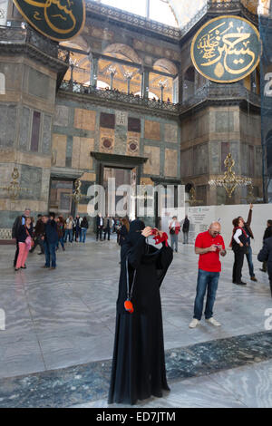 Muslim woman at Hagia Sophia, Ayasofya Muzesi mosque museum wearing niqab using smartphone taking photographs, Istanbul, Turkey Stock Photo