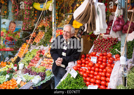 Turkish shopkeeper selling fresh vegetables on sale at food and spice market in Kadikoy district Asian side of Istanbul, Turkey Stock Photo