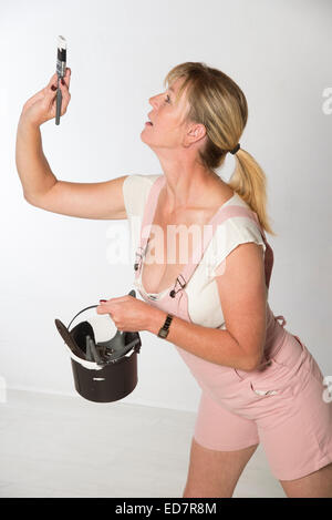 Woman wearing pink overalls holding paint brush Stock Photo