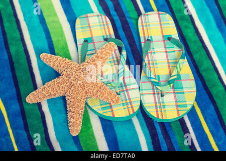 Beach towel and flip flops with a vintage effect. Stock Photo
