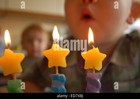 3  year old boy blowing out candles on birthday Stock Photo