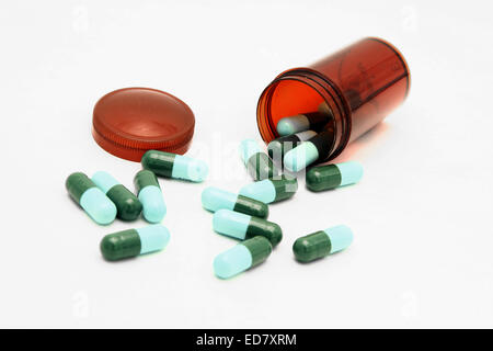 isolated capsules spilling out from small bottle Stock Photo