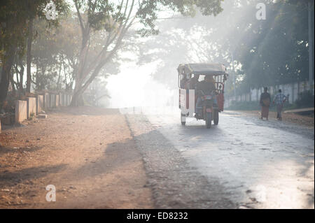 Rays of sun light cutting through the trees and shining on a tuk tuk Stock Photo