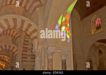 CORDOBA ANDALUCIA SPAIN INTERIOR MOSQUE CATHEDRAL COLOURS FROM A STAINED GLASS WINDOW LIGHTING AN ARCH Stock Photo