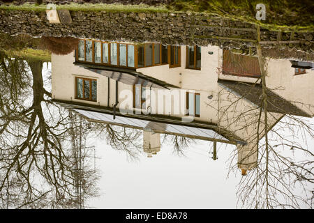 Solar panels on a house roof reflected in the Leeds Liverpool canal near Skipton, UK. Stock Photo