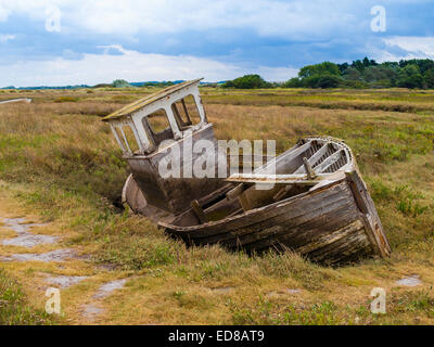 An old derelict decaying abandoned wooden boat on a salt marsh at Thornham North Norfolk An old derelict decaying abandoned wooden boat on a salt marsh at Thornham North Norfolk