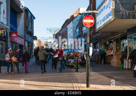 Looking up Castle street in Hinckley as a teenager gives a donation to a Big Issue seller Stock Photo