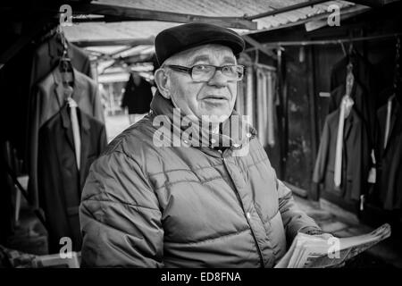 Sales person at Rozycki Bazaar in front of his merchandise Stock Photo