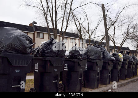 Overflowing garbage piled high in row of bins on street waiting for pickup Stock Photo