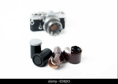 Analog photo reels with vintage camera out of focus in background on white Stock Photo