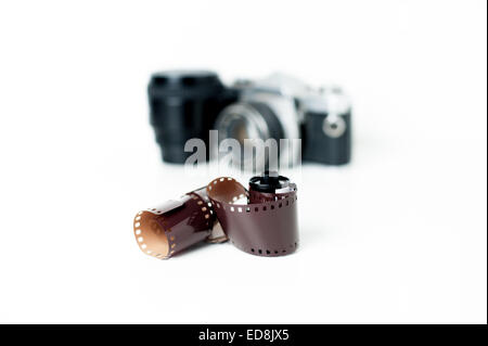 Analog photo reel with vintage camera and a lens out of focus in background on white Stock Photo