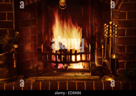 Warmly glow of a traditional winter scene as the open fire in a home radiates glowing light as wood embers and coal burn hot Stock Photo