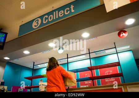 A woman shopper picking up her purchase from the  'collect' area counter at an Argos discount catalogue store, interior, UK Stock Photo