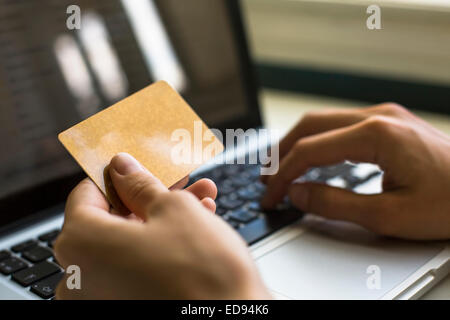 Card (with place for your text) in hand and entering security code using laptop keyboard. Stock Photo