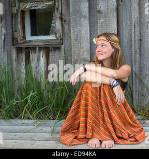 Beautiful young hippies girl sitting outdoors in the countryside, looking blank space on the left. Stock Photo