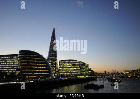 View along River Thames to City Hall and The Shard at Dusk with HMS Belfast moored in the Thames London England Stock Photo