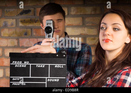 Close up Young White Woman with Clapper Board, Looking at Left Side, In Front Male Photographer Taking Picture. Stock Photo