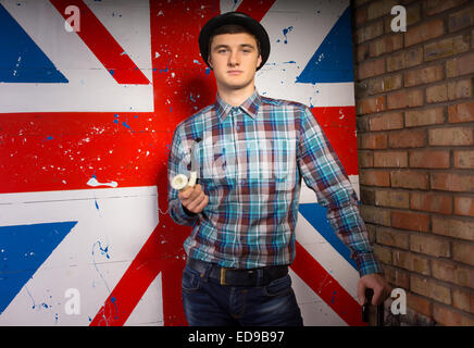 Close up Young Handsome Man in Trendy Fashion with Smoking Pipe and Cane Standing in Front Britain Flag Print While Looking at t Stock Photo