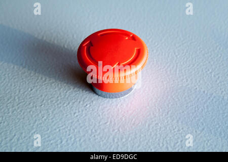 Red emergency stop switch reset industrial button on blue steel panel Stock Photo