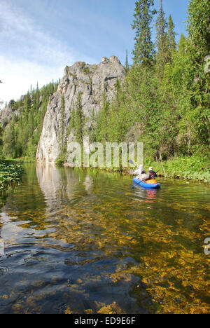 Russia, Komi Republic, summer, taiga. Canoe sailing against the background of the cliff. Stock Photo