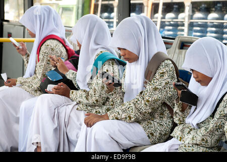 Balinese school girls with their smart phones on a bus in Bali, Indonesia. Stock Photo