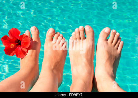 feet of a young couple by the pool with a red flower Stock Photo