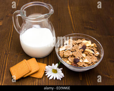 Jug of milk and cereal in bowl on wooden table Stock Photo