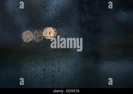 lights of traffic seen through wet windshield during rainfall in darkness Stock Photo