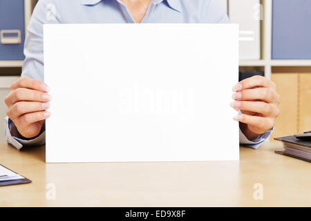 Two female hands holding empty white sheet of paper in an office Stock Photo