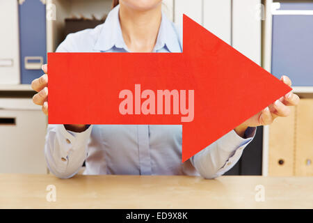Businesswoman holding big red arrow symbol sign to the right in front ...