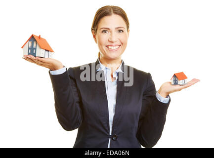 Smiling real estate broker holding two small houses on her hand Stock Photo