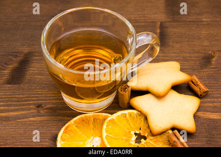 Tea and biscuits with orange and cinnamon on wooden table seen close Stock Photo