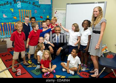 US President Barack Obama smiles as he poses for a group photo with elementary school students at MacDill Air Force Base September 17, 2014 in Tampa, Florida. The President jokingly told the students not to make rabbit ears behind him which they couldn't resist doing. Stock Photo