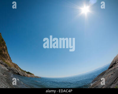 A wide angle, fisheye view of the midday sun and the Strait of Juan de Fuca off the coast of Victoria, British Columbia, Canada. Stock Photo