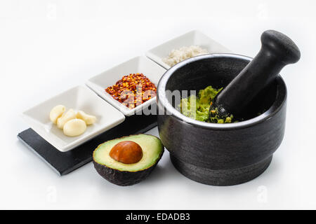Pestle and Mortar filled with avocado and chili pepper garlic for making Guacamole. Stock Photo