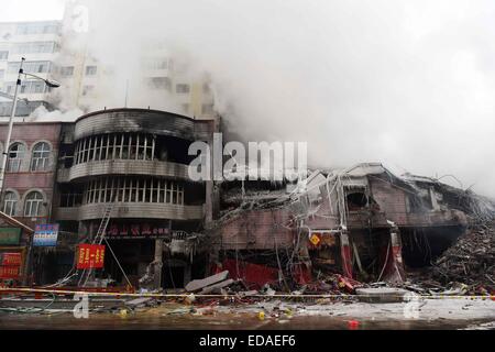 (150104) -- HARBIN, Jan. 4, 2015 (Xinhua) -- Smokes rise from a burnt warehouse at the Beifangnanxun ceramics market in Daowai District, Harbin, capital of northeast China's Heilongjiang Province, Jan. 4, 2014. The warehouse blaze in Harbin City that killed 5 firefighters still hasn't been completely extinguished, local firefighters said on Sunday. As of 10:40 a.m. Sunday, a residential building next to the warehouse was still smoldering. Rescuers said that the source of the fire has been hard to determine due to the building's complicated structure, and the building is at risk of collapsing. Stock Photo