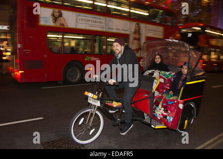 A rickshaw with customers in Oxford Street at night, London, England, United Kingdom Stock Photo