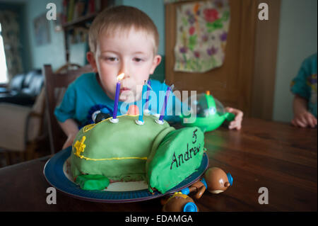 Boy blowing out birthday candles on cake Stock Photo