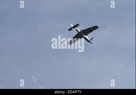 P51 Mustang at the top of a loop during a display with an airliner in the background Stock Photo