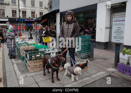 Man walking his dogs at the Sunday Farmers Market in Brixton Market, London Stock Photo