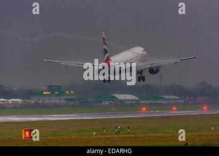 January 3rd 2015, Heathrow Airport, London. Low cloud and rain provide ideal conditions to observe wake vortexes and 'fluffing' as moisture condenses over the wings of landing aircraft. With the runway visible only at the last minute, several planes had to perform a 'go-round', abandoning their first attempts to land. PICTURED: A wake vortex spirals off the wingtip of a British Airways Airbus A321 as it lands on Heathrow's Runway 27 Left. Stock Photo