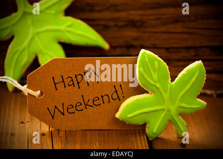 Brown Organic Label With English Text Happy Weekend On Wooden Background With Two Leaf Cookies And Frame Stock Photo