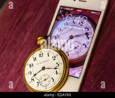 An Antique railroaders pocket watch from 1900 and a modern iPhone from 2011 with an image of the watch in the screen. Stock Photo