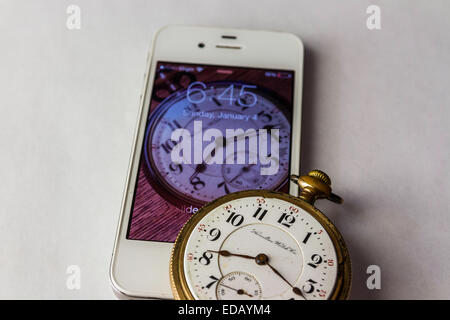 An Antique railroaders pocket watch from 1900 and a modern iPhone from 2011 with an image of the watch in the screen. Stock Photo